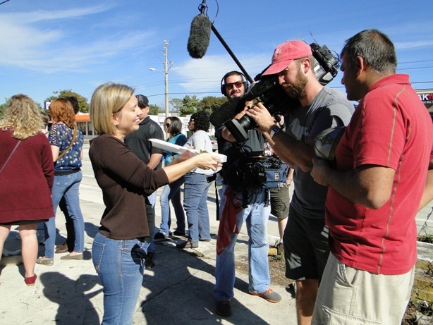 woman being featured in cooking channel segment with videographers and a microphone raised above