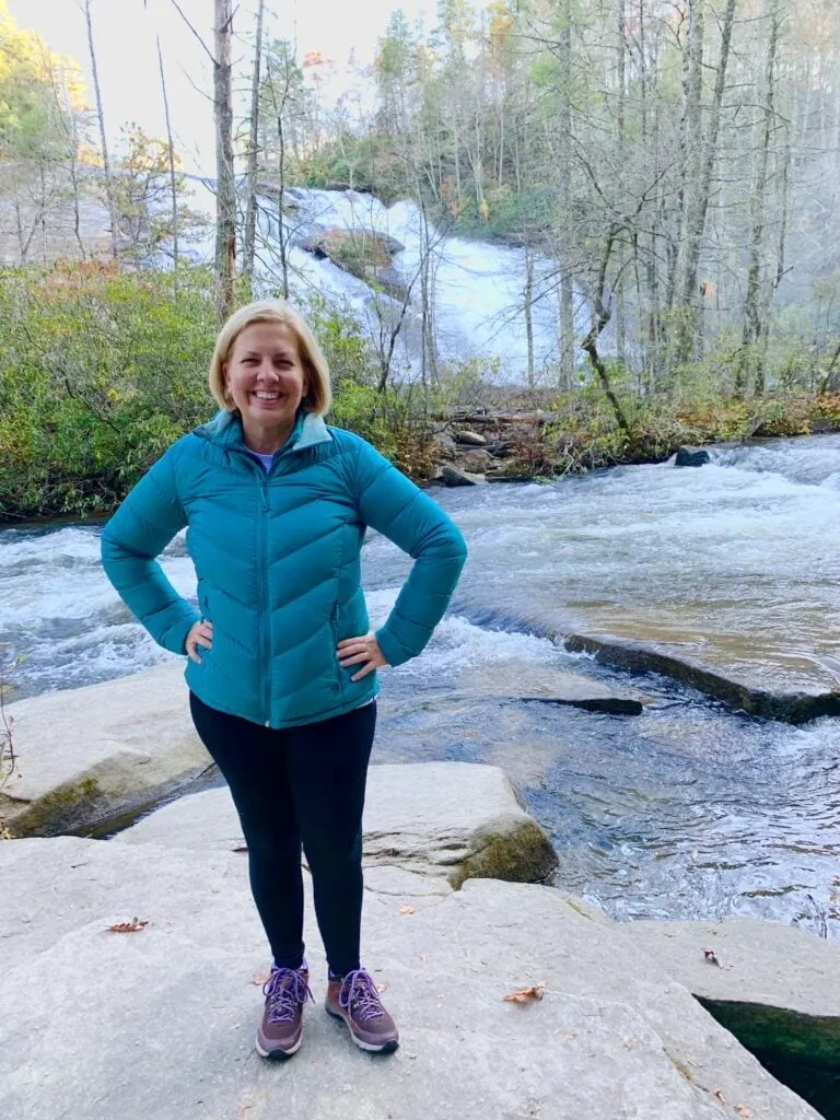 woman standing on rocks near waterfall