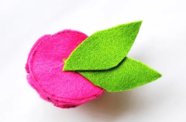 two green felt leaves attached to the bottom of a pink flower
