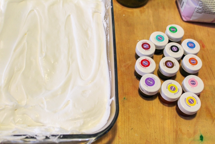 glass dish full of whipped cream with tubes of food coloring on the table