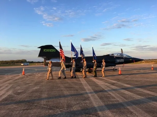 JROTC holding flags walking by a jet