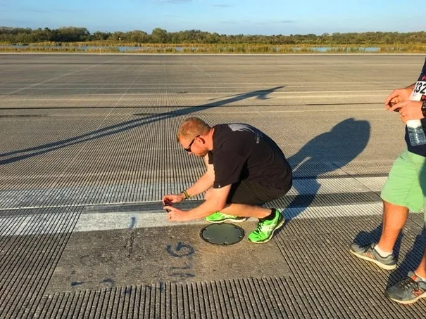 man kneeling on runway taking pictures with a phone 