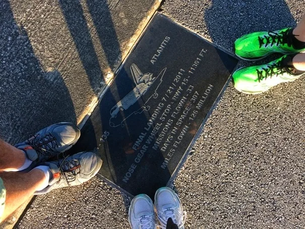three pairs of sneakers standing on plaque with space shuttle image