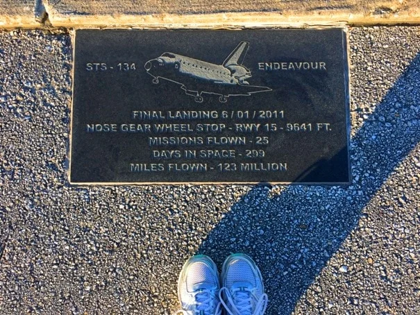 tennis shoes standing next to plaque with space shuttle