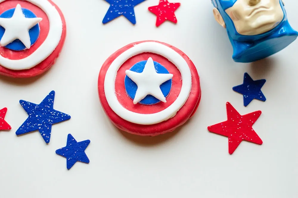 red cookie with white circle and blue dot in center topped with white star captain america head