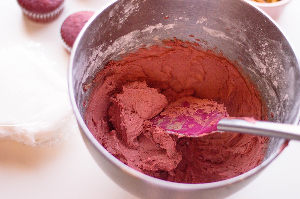 bowl of red homemade buttercream frosting with spatula