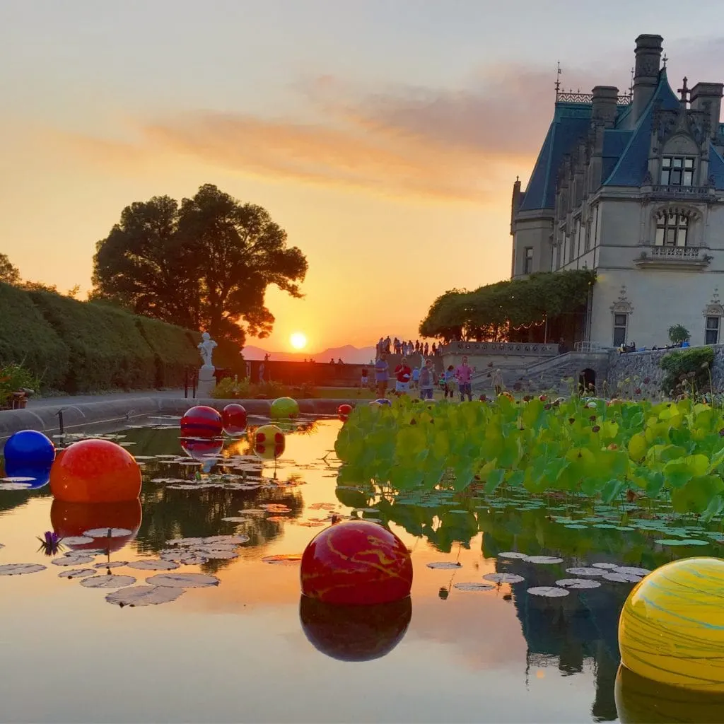 sunset behind the mountains Chihuly glass in pond at Biltmore Estate