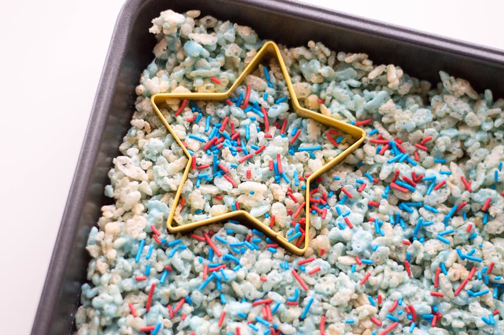 star cookie cutter in a pan of red white and blue Rice Krispies treats with sprinkles