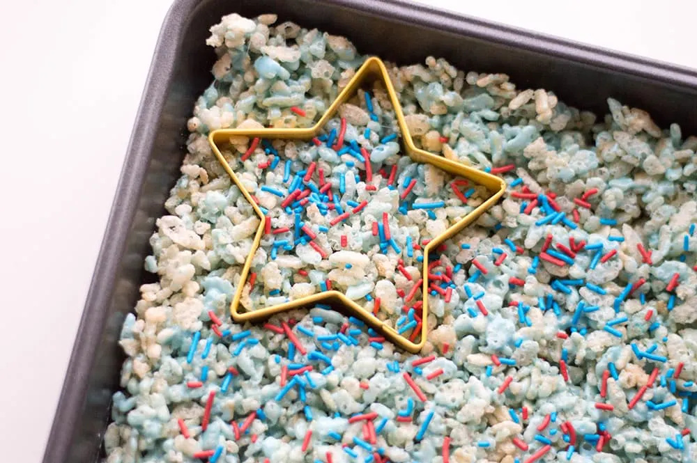 star cookie cutter in a pan of red white and blue Rice Krispies treats with sprinkles