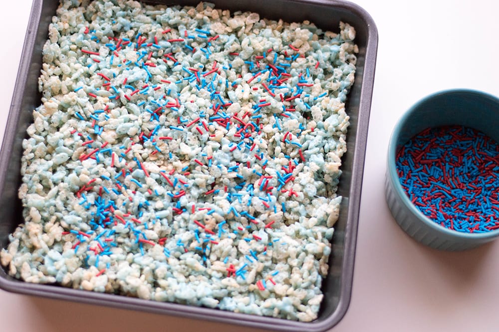 red white and blue Rice Krispies treats in a baking pan with sprinkles