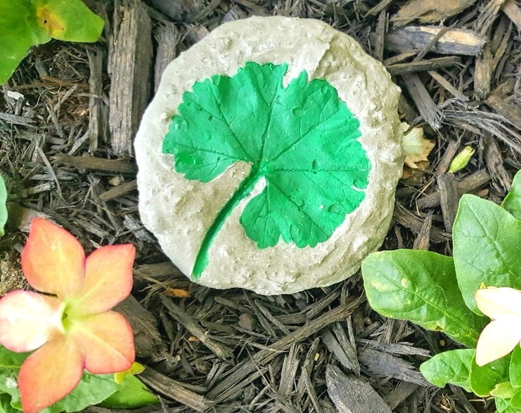 Green Leaf imprint in grey cement decorative garden stone against mulch
