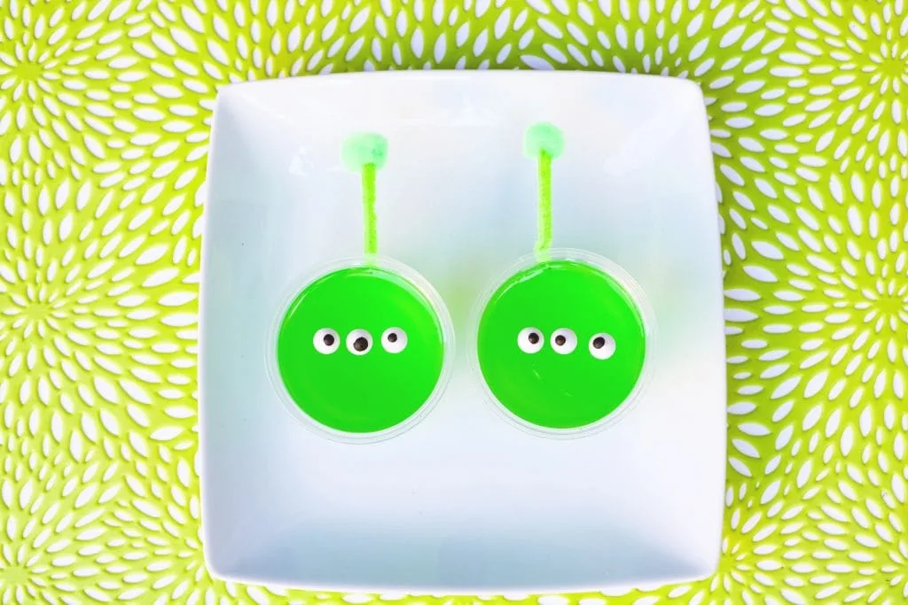 green jello alien snack cups with candy eyes and pipe cleaner antennas