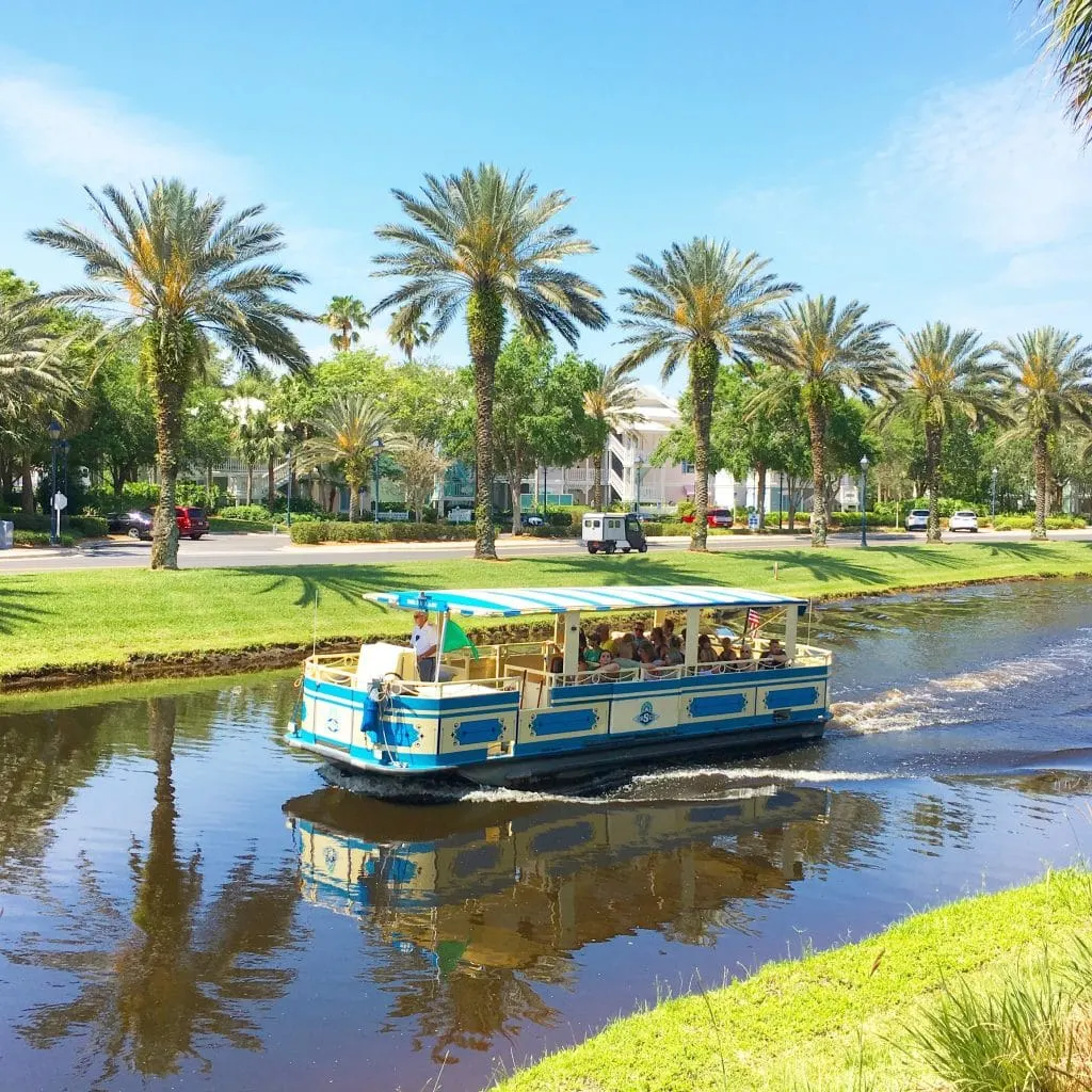 boat in canal with green grass on banks and palm trees at Disney World