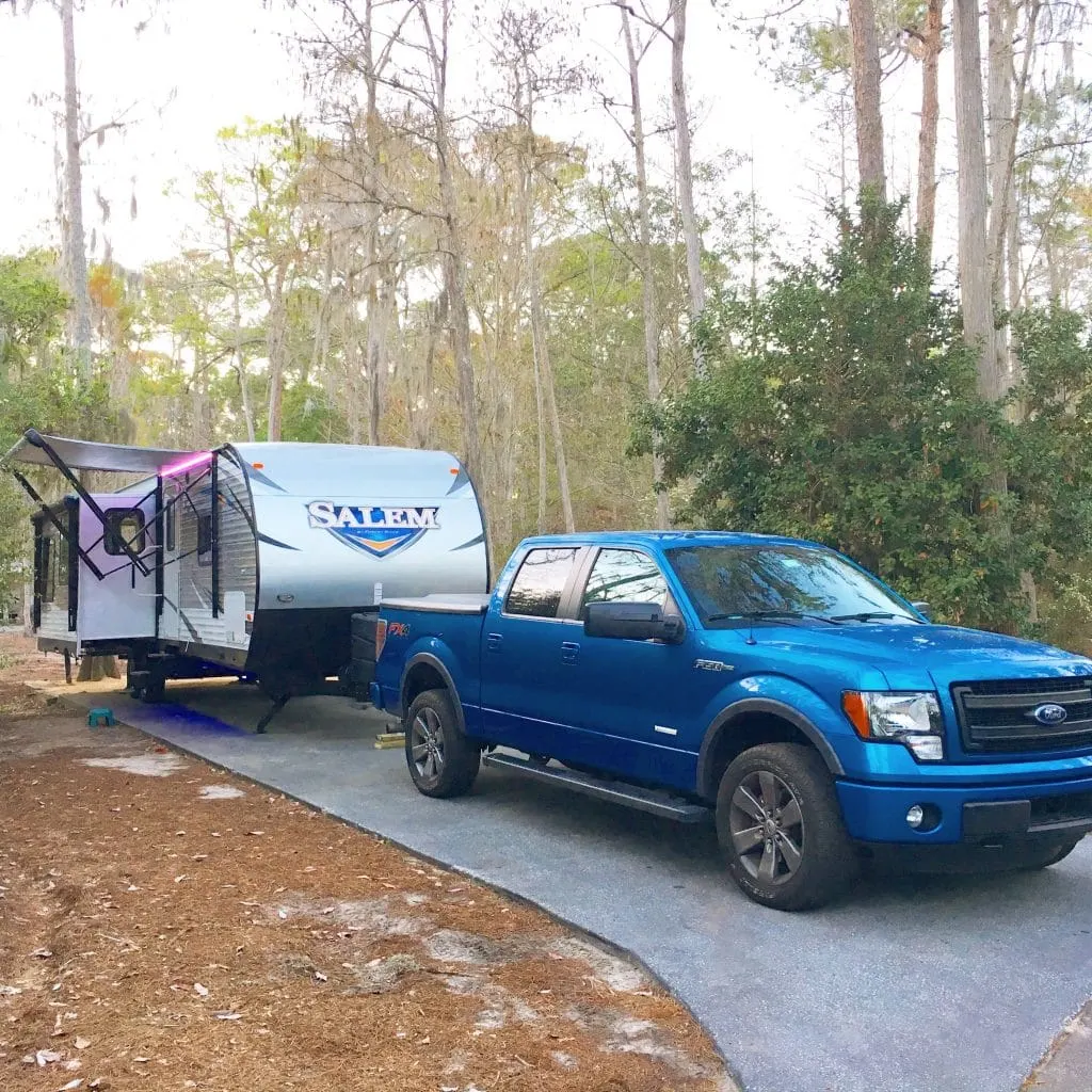 blue truck hooked up to travel trailer rv in campsite