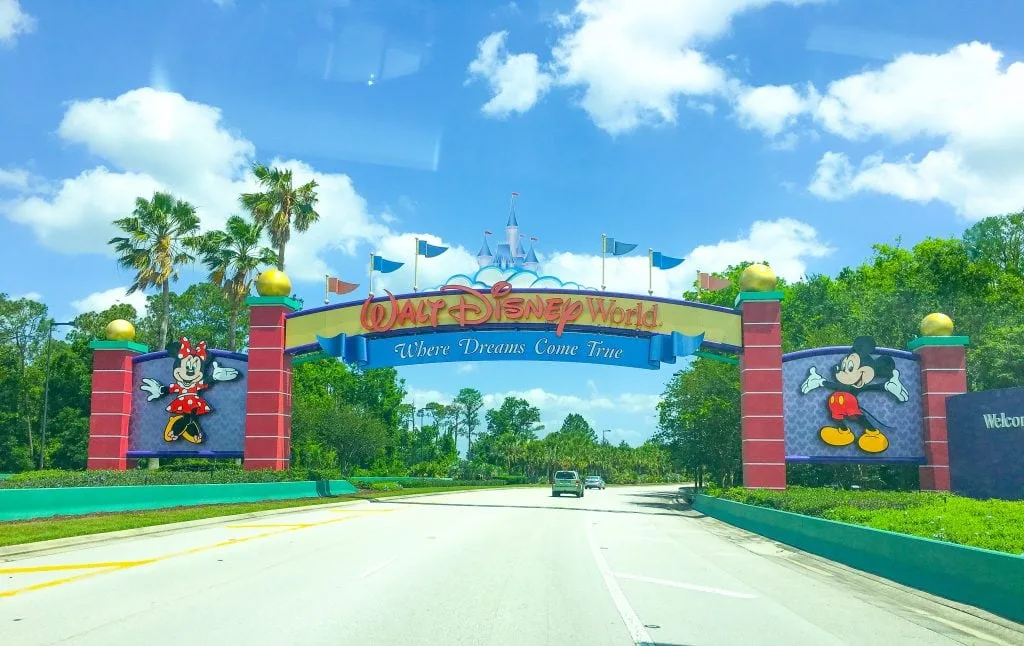 Walt Disney World Sign with palm trees, blue sky and white clouds in the background