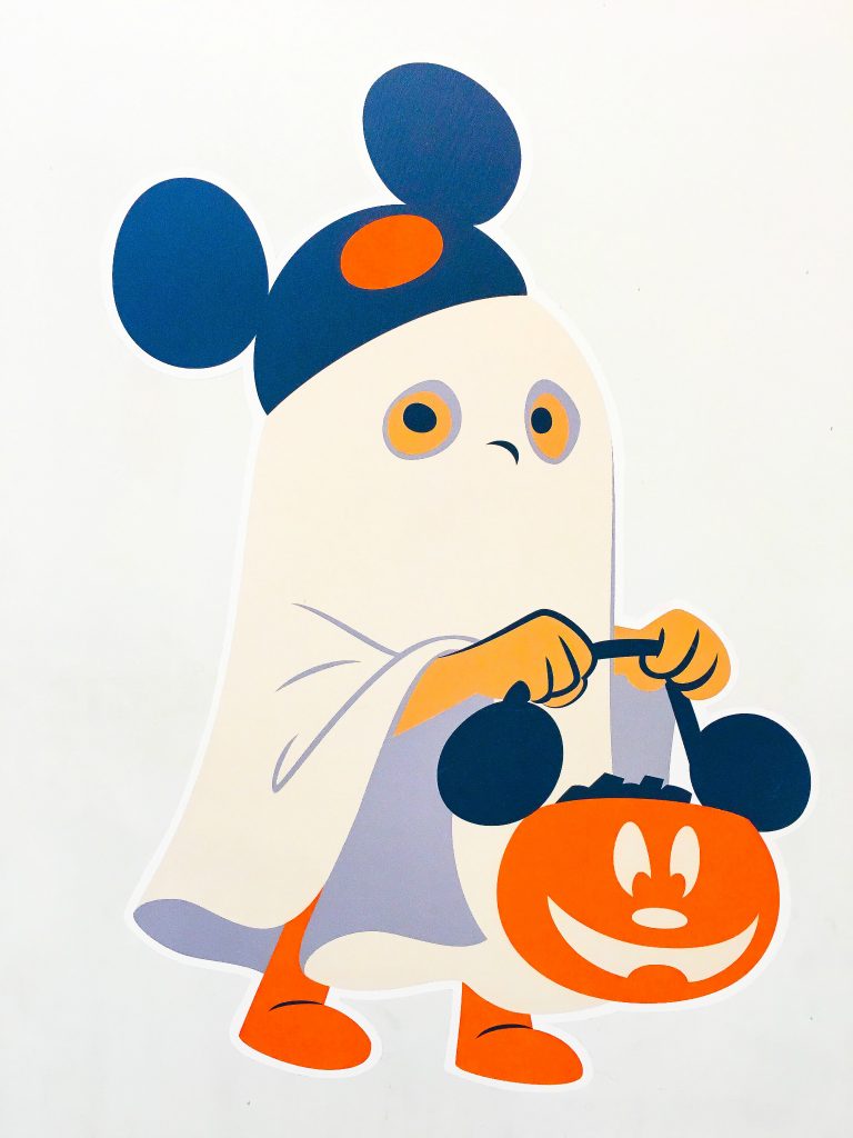 cartoon child wearing a white sheet ghost costume with Mickey Mouse ears hat holding an orange pumpkin with mouse ears