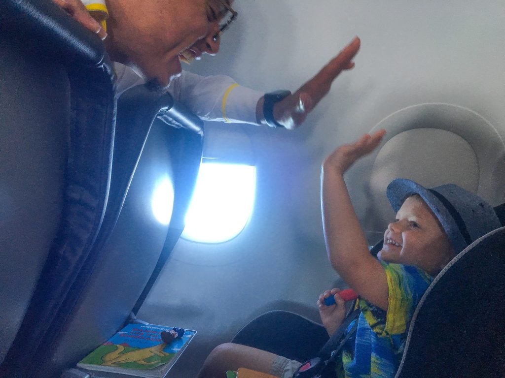 boy on plane giving high five to flight attendant