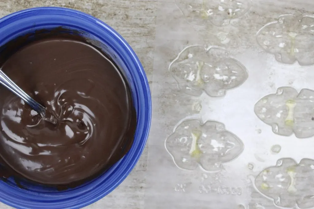 melted chocolate in a blue bowl next to frog candy molds