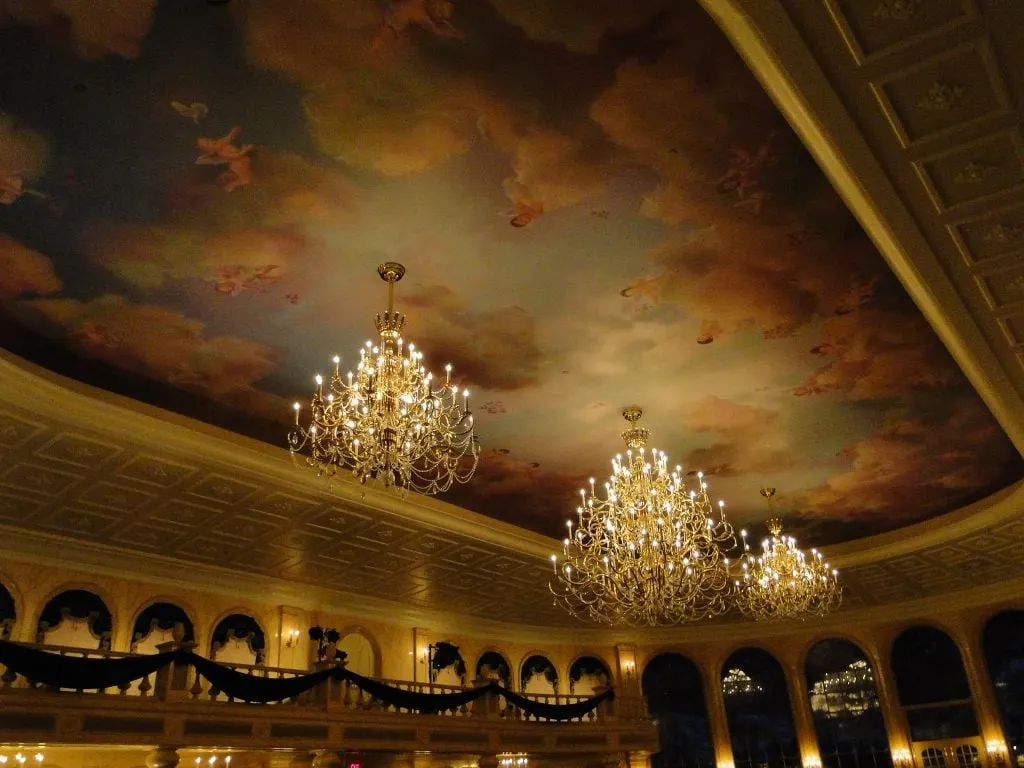 Painted ceiling with clouds and glass chandeliers at Be Our Guest Restaurant