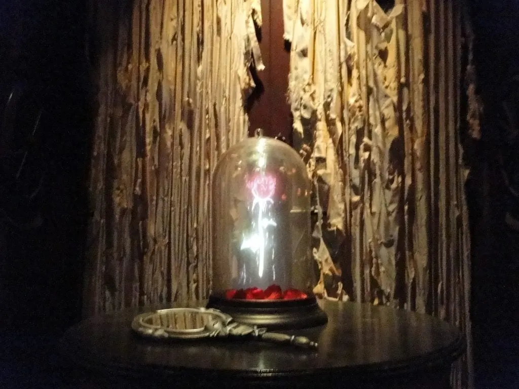 holographic rose under glass dome on table with mirror beside