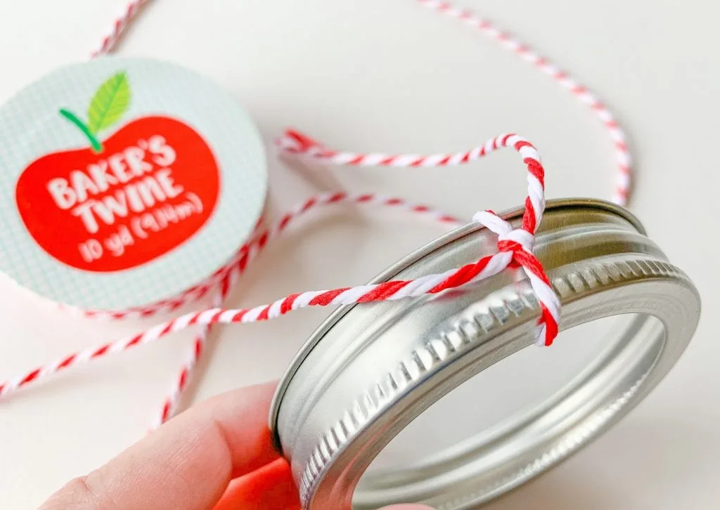 red and white bakers twine tied around canning jar lid ornament