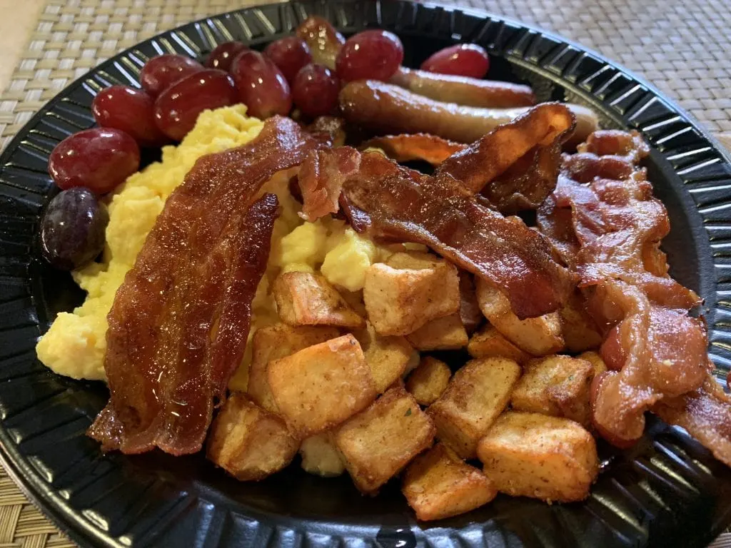 hash browns, potatoes, bacon, eggs, and grapes on black plate for breakfast at Discovery Cove Orlando Florida