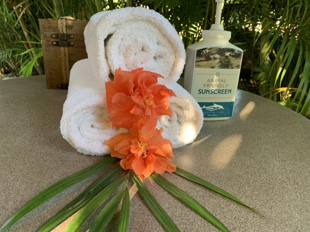 rolled towels with peach hibiscus flowers and sunscreen
