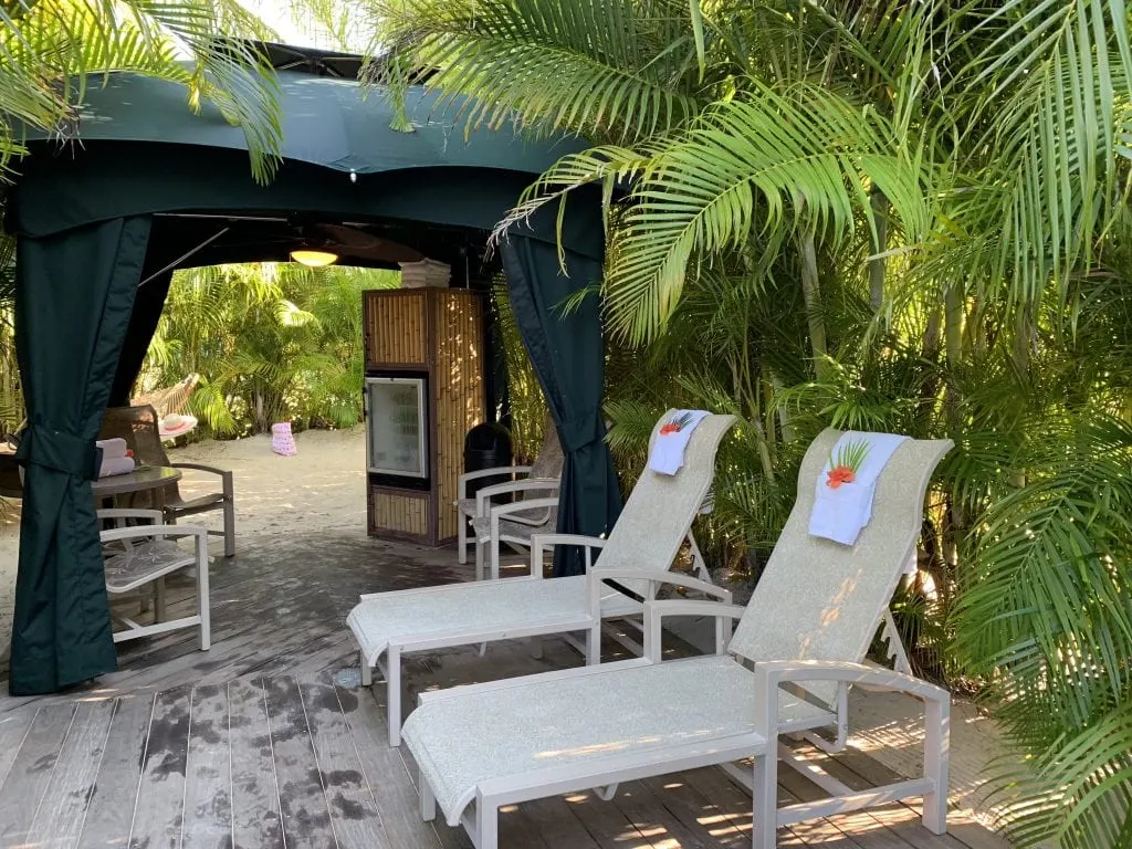 cabana surrounded by palm trees in the sand with lounge chairs at Discovery Cove Orlando Florida