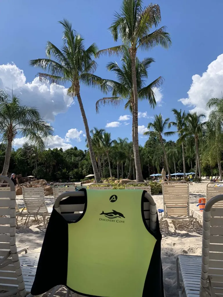 discovery cove swim vest on beach chair in sand with palm trees and blue sky Orlando Florida
