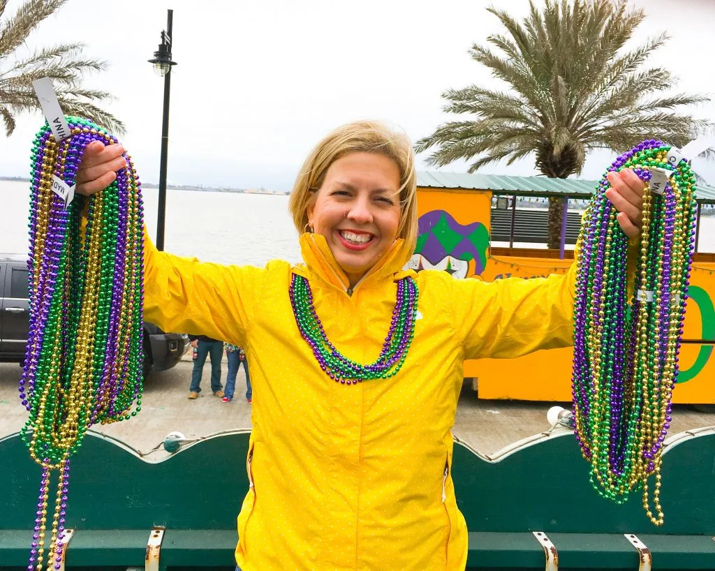 Kim holding mardi beads in hands wearing yellow jacket on lake Charles Mardi Gras parade float