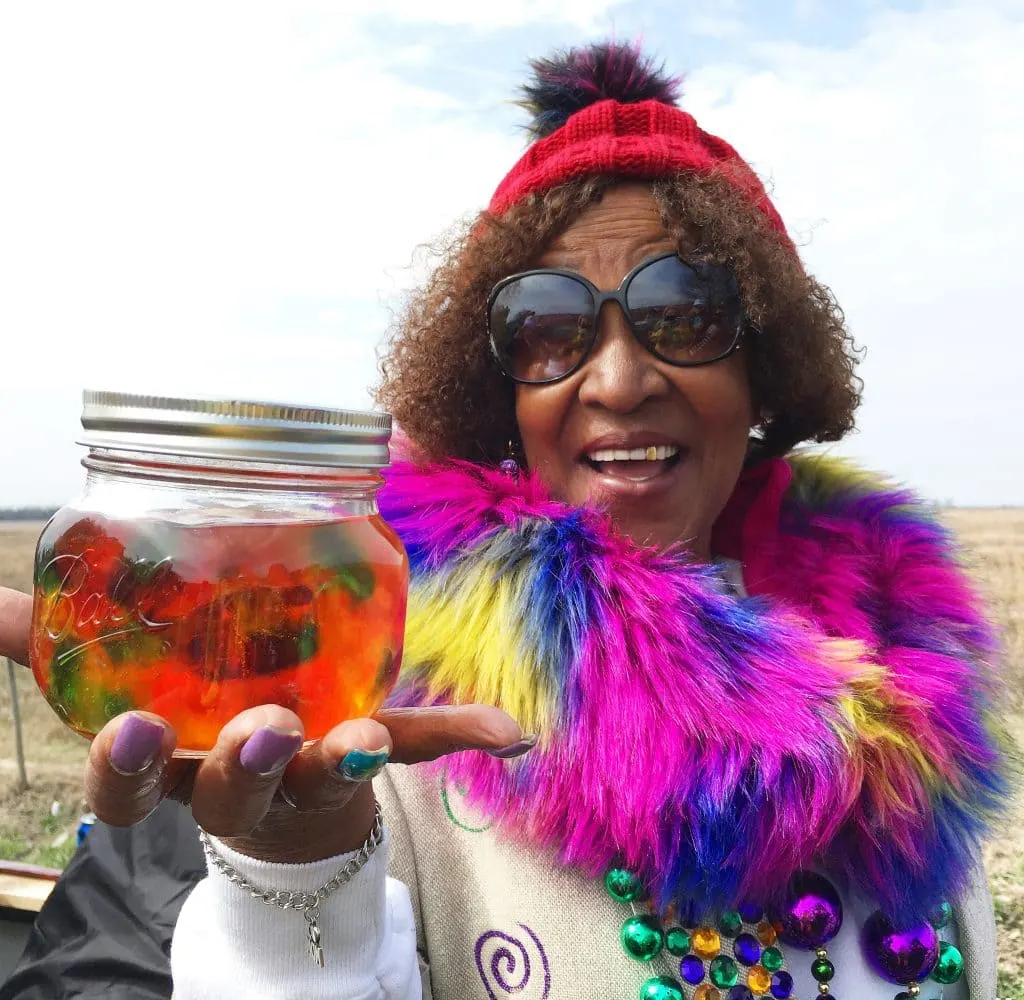 woman wearing plink boa holding mason jar full of tequila and gummy worms