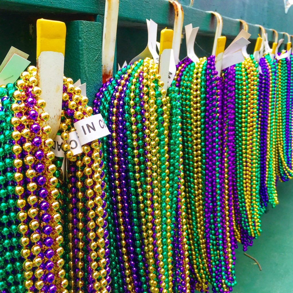 purple green and gold Mardi Gras beads hanging on hooks