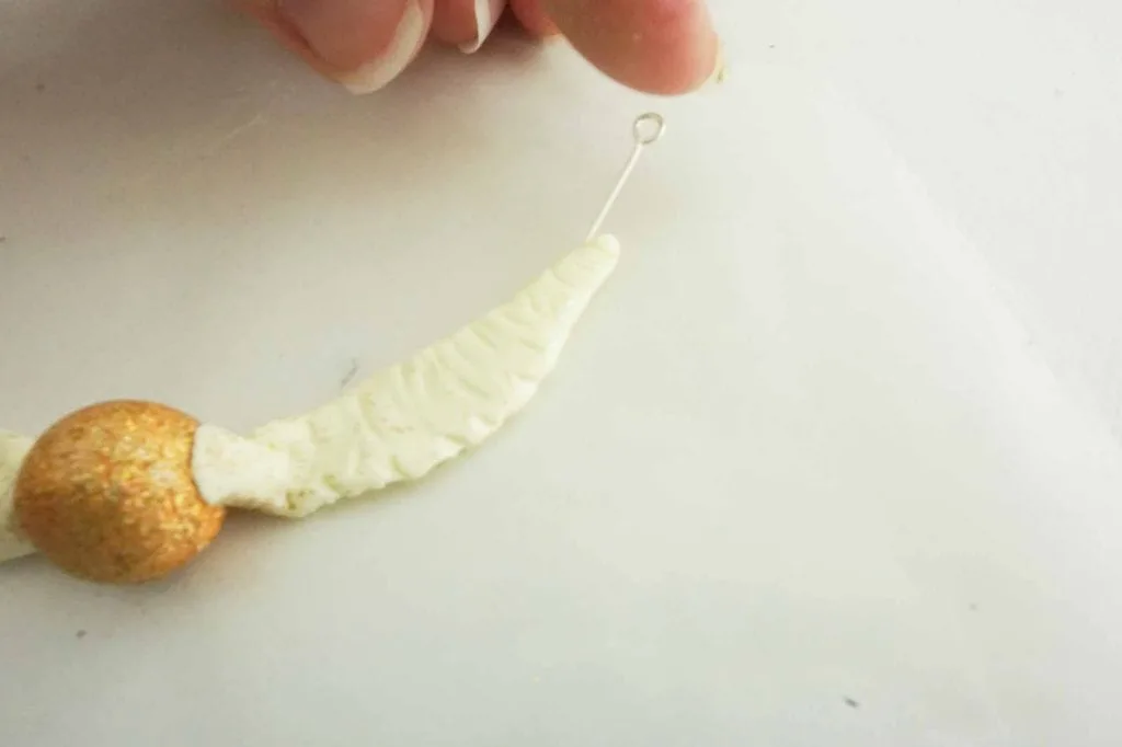 eye pin in clay of golden snitch wing feather
