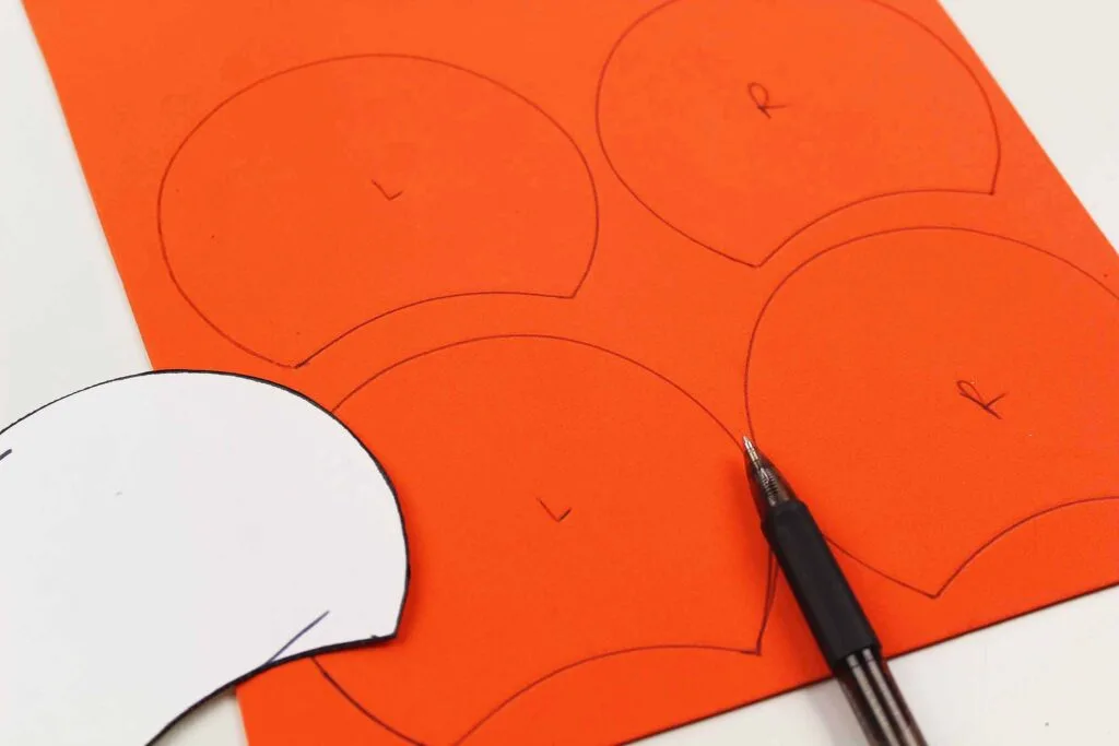 tracing a Mickey Mouse ear template on orange foam