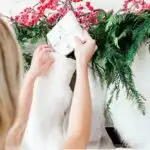 woman putting white small present in Christmas stocking on fireplace
