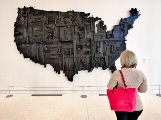 woman holding pink purse looking at wooden United States artwork