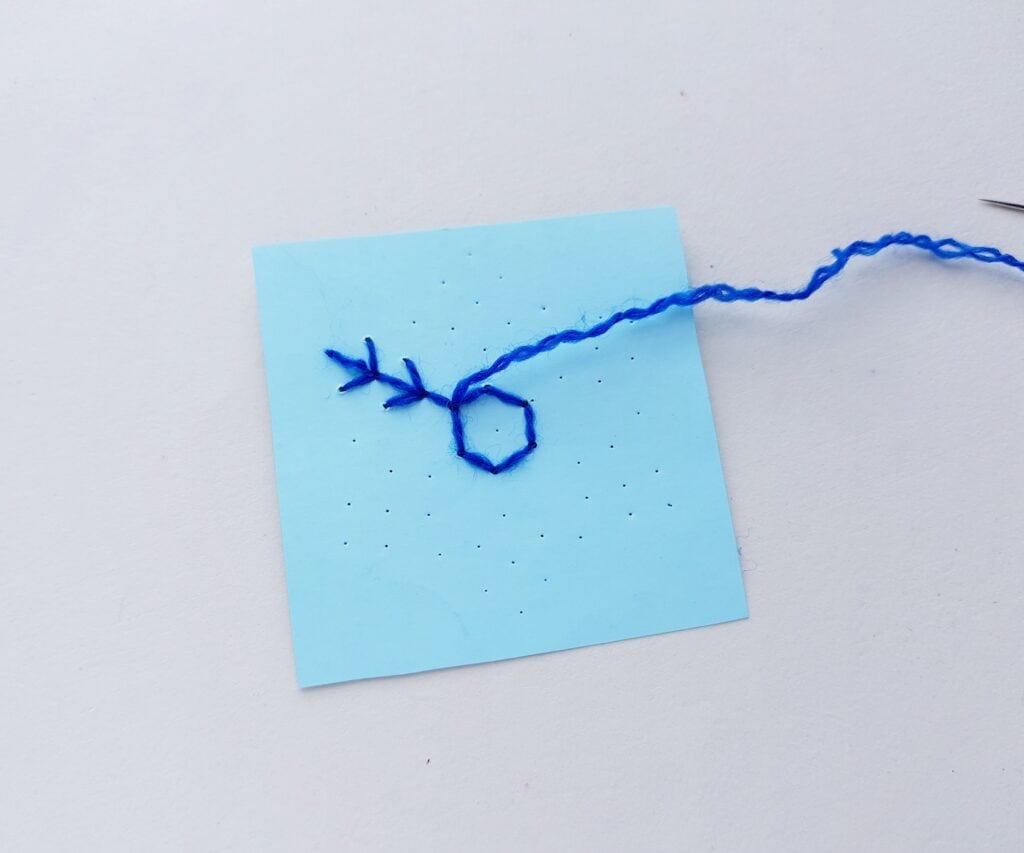 blue yarn stitching a snowflake pattern on blue cardstock
