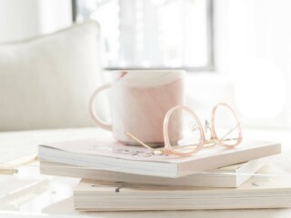 stack of books with coffee cup and glasses on top