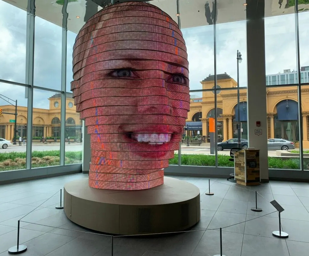 art statue head with digital display of a face on it