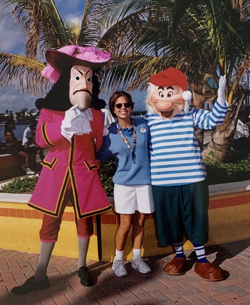 woman standing with Captain Hook and mr. smee characters in front of palm trees