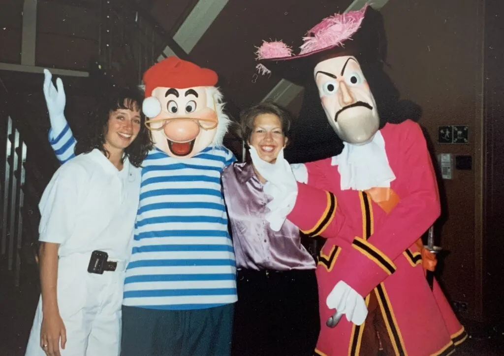 two women taking a picture with Captain Hook and mr. see onboard disney cruise line