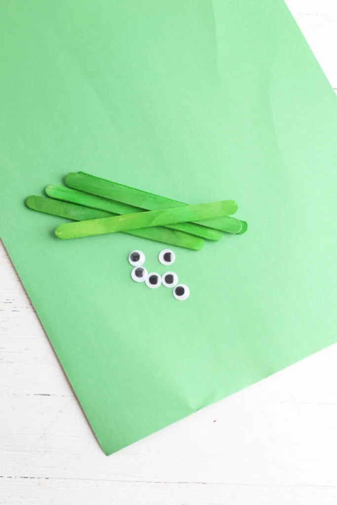 green construction paper with popsicle sticks and googly eyes