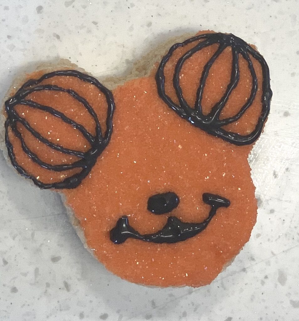 making Mickey Mouse smile with black frosting on pumpkin treat