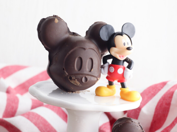 mickey shaped chocolate mold on white pedestal next to plastic Mickey Mouse figurine