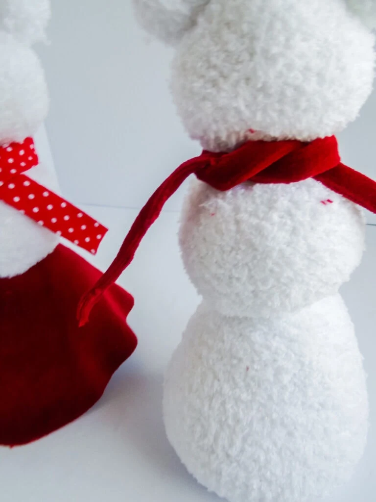 white sock snowman with red scarf tied around neck