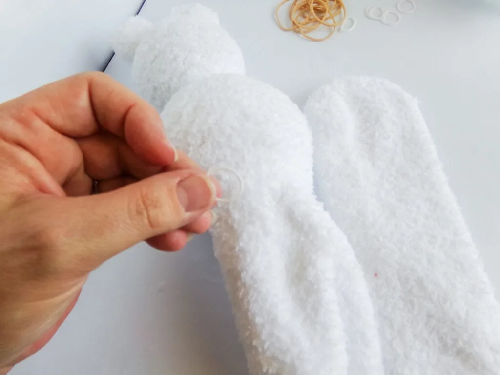 wrapping a rubber band around a stuffed white sock