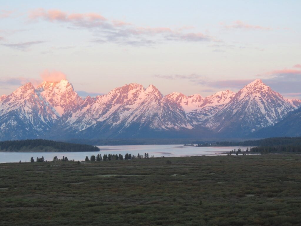 pink light of sunrise bathing Grand Teton mountain range