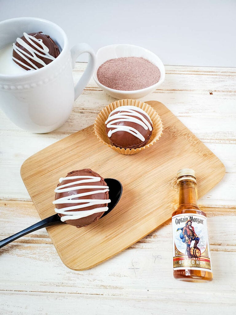 Spiced Rum Hot Chocolate Bombs on wood with spiced rum bottle