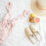 bathing suit, shoes, hat and citrus fruit on linen blanket
