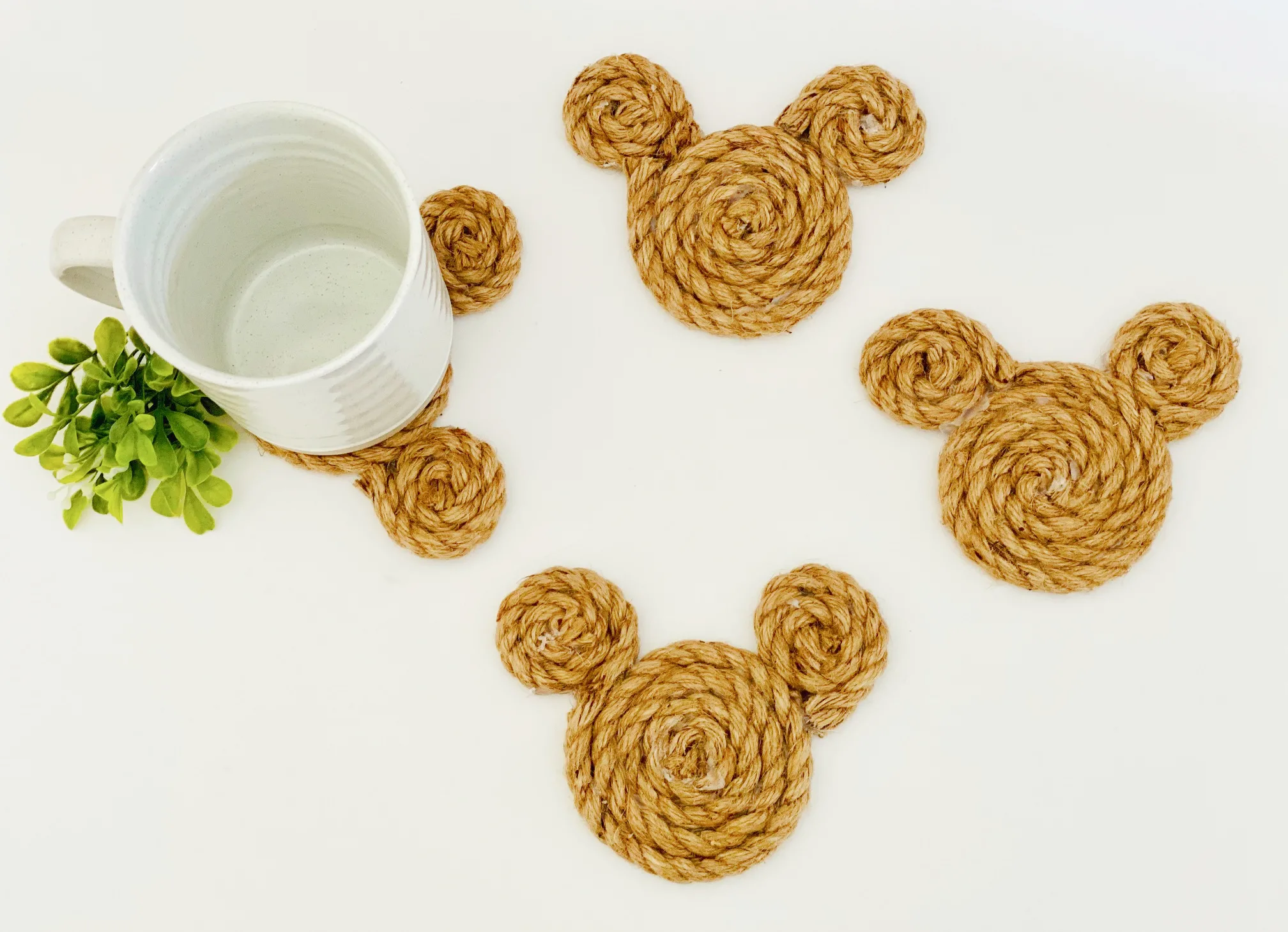 four rope Mickey coasters with a white coffee mug on one coaster